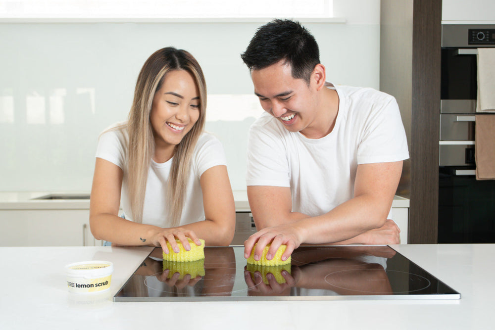 Man and Woman Using E&B Dishwashing Paste on Sponge – Removes Grease Easily from Plates and Cookware